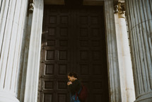 a girl praying in front of the doors of a church 