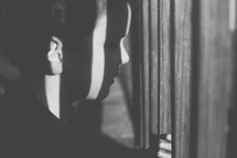 sunlight on a boy child's face as her looks through bars 