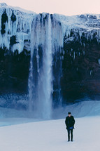 man watching a frozen waterfall and ice and snow 