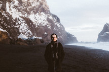 a man walking on a beach and snow on sea cliffs 