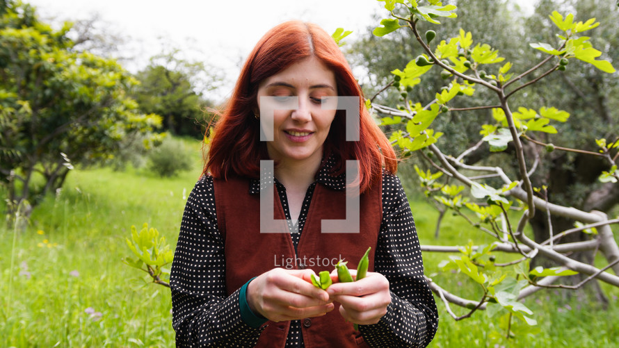 Girl red hair smiles and opens pods of peas