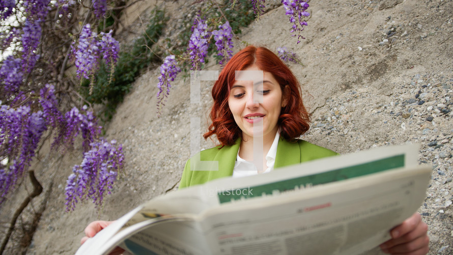 Businesswoman reading newspaper under the wisteria flower