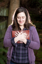 woman holding a Bible to her heart