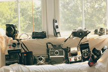 Variety of old cameras in front of a window.