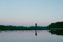 a man standing on a lake dock 
