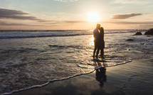 a couple embracing on a beach at sunset 