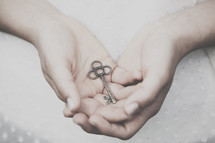 Hands holding a silver key.