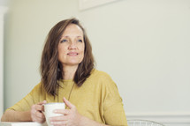 a woman holding a coffee cup and thinking 