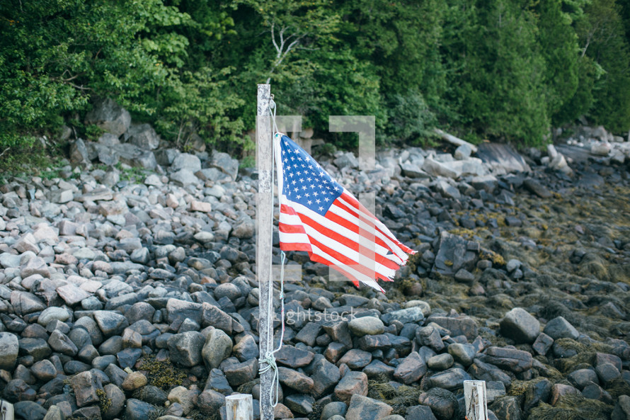 American flag on a rocky shore 