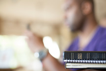 Man texting near a Bible.