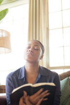 woman looking up to God in prayer while holding a Bible 