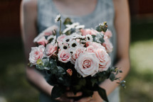 a woman holding a bouquet of pink roses 
