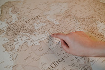 finger pointing to a world map 