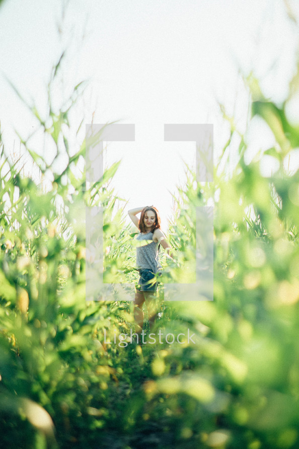 a teen girl standing in a corn field 