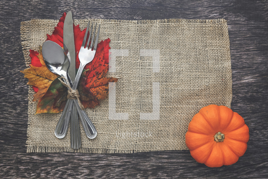 silverware on fall leaves on a burlap placemat 