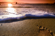 tide washing onto a shore at sunset 
