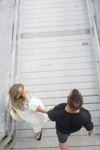 high angle of couple holding hands walking on a boardwalk.