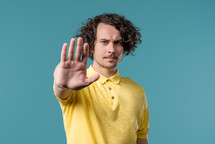 Serious american man showing rejecting gesture by stop finger sign. Dont play with me. Guy isolated on blue background. High quality