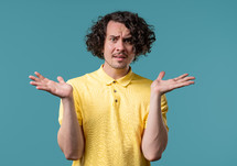 Confused man, shoulders up - can't help, makes gesture of I dont know. Difficult question, guilty reaction, puzzled teenage guy on blue background. High quality