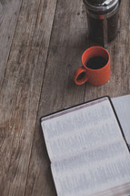 An open Bible, notebook, coffee mug and french press