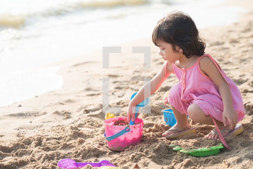 little girl playing in the sand on a beach 
