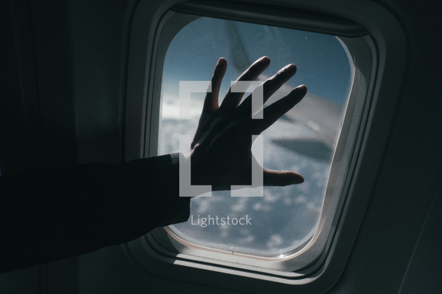 hand touching an airplane window 