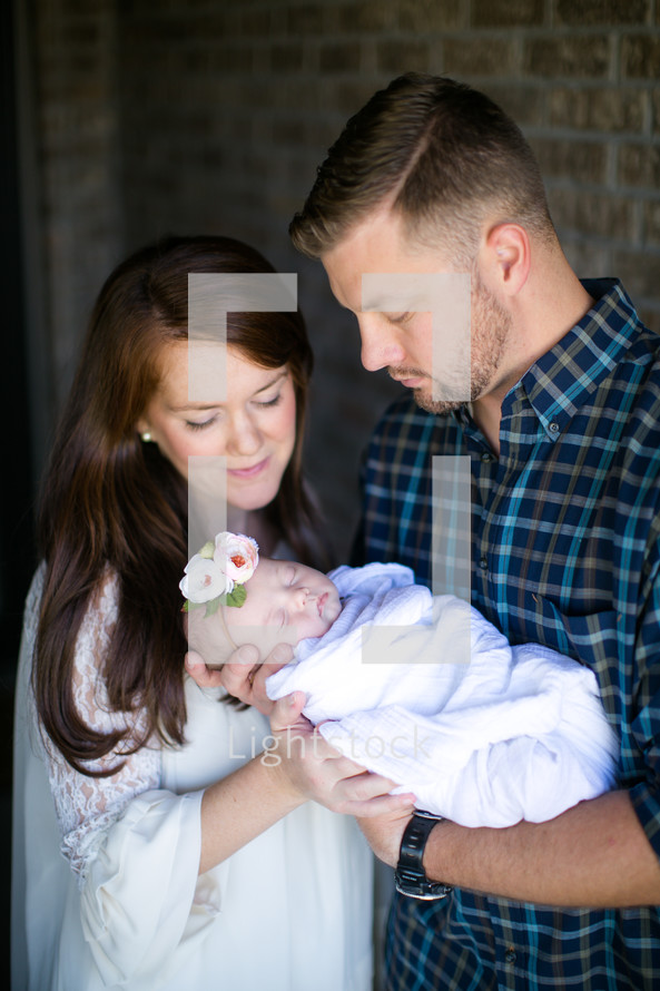 mother and father with a swaddled newborn baby girl 
