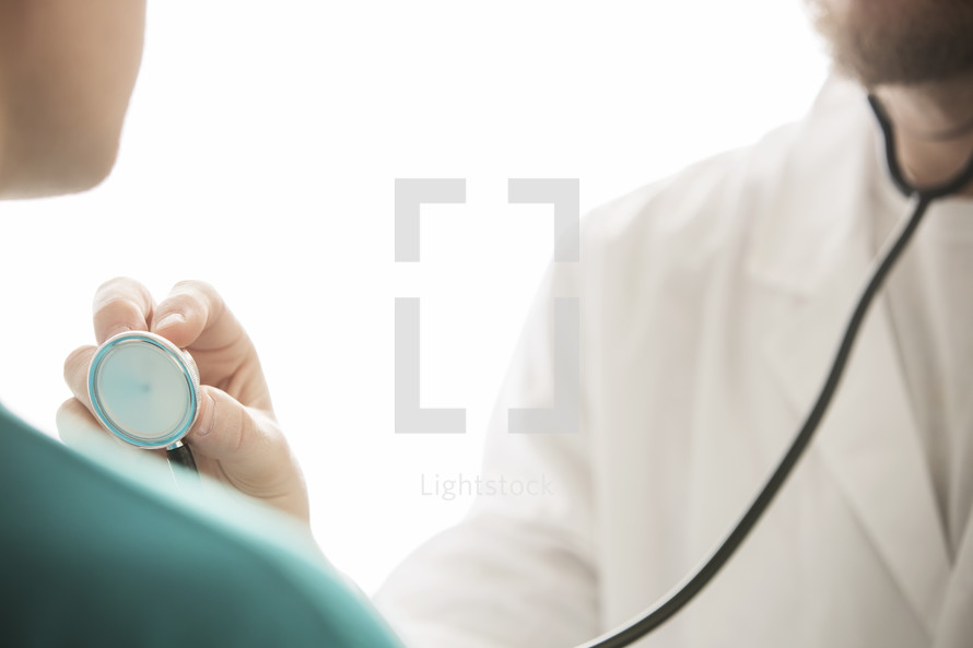 doctor checking patient with stethoscope.