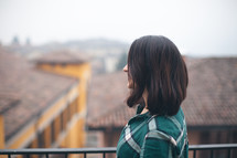 A woman in a green shirt looking out over a city