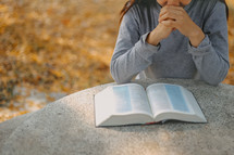 a person reading a Bible at an outdoor table 