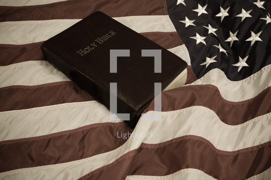 Holy Bible on waving American flag with retro look.