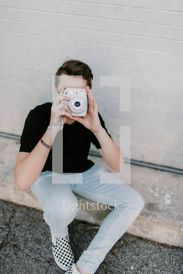 a young man holding a polaroid camera 