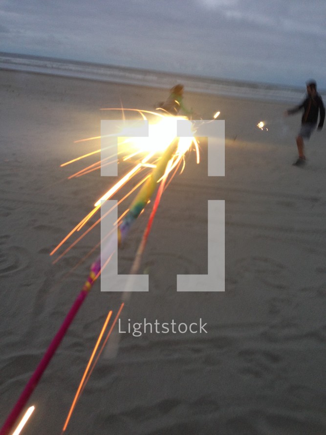 holding sparklers on a beach 