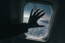 hand touching an airplane window 
