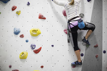 woman climbing an indoor rock wall.