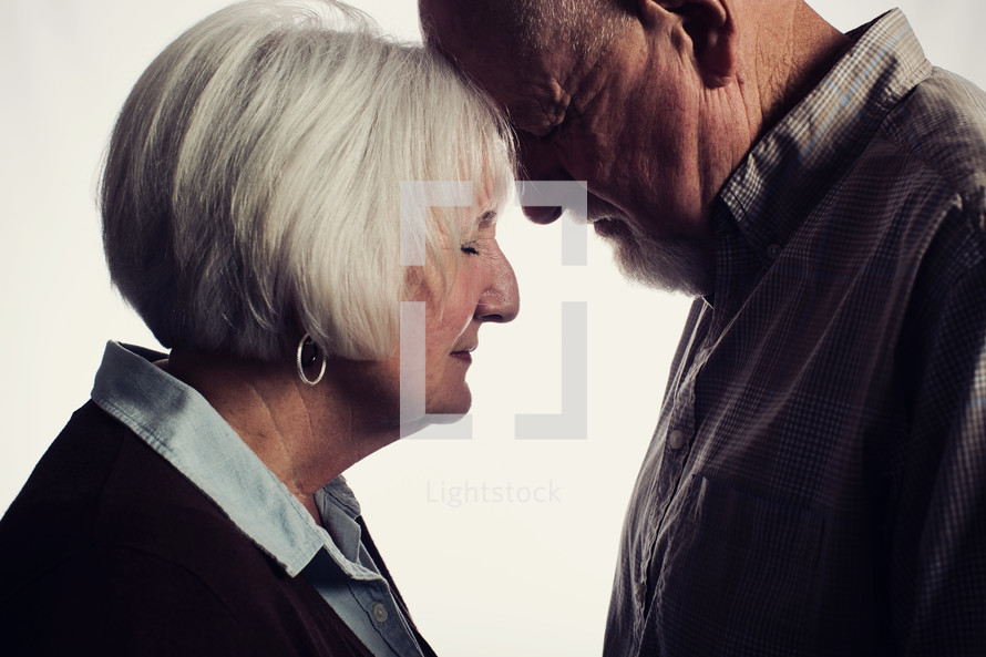 elderly man and woman with head bowed in prayer 