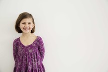 portrait of smiling young girl against white wall.