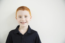 A smiling red haired boy.