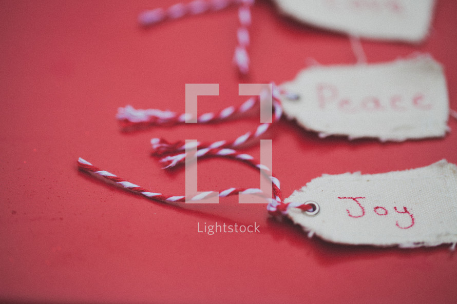 Christmas gift tags, the first one reading "Joy", on a red background.