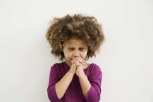 a little girl in prayer with eyes closed tightly.