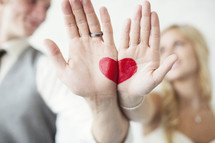 bride and groom with a red heart painted on their hands 