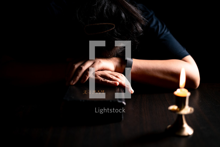 Bible and candlelight with praying woman