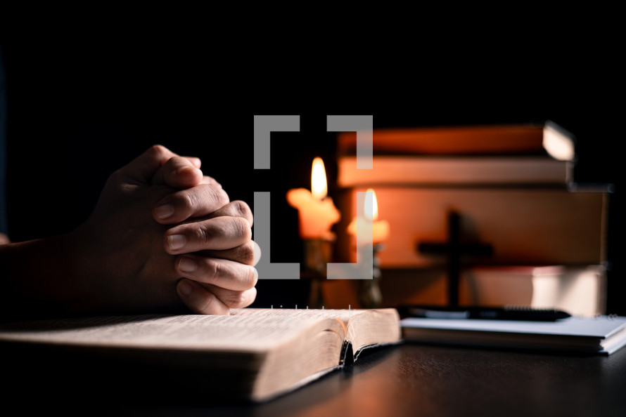 Bible and candlelight with praying hands