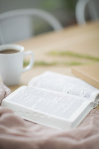 open Bible and coffee mug on a table 