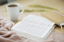 open Bible, coffee, mug, and journal on a table 