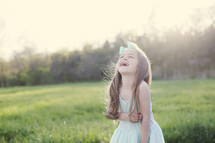 a little girl standing in a field of green grass laughing