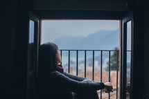 A young woman gazing out a barred window
