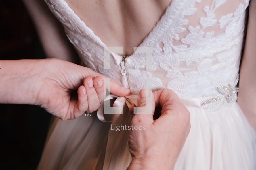 tying a bow on a brides dress 
