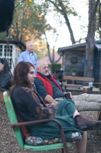 people sitting around talking at an outdoor gathering 