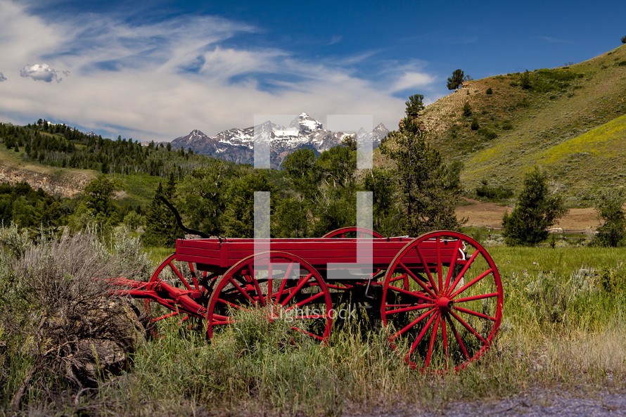 red wagon in a valley and mountain peaks 